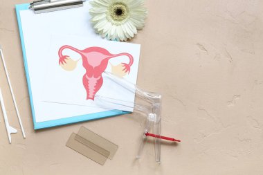 Jinekolojik spekulum, kadın rahminin çizimi, pano ve bej arkaplan üzerindeki pap smear test araçları