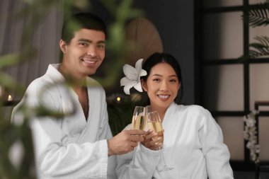 Spa salonunda şampanya bardakları olan genç bir çift.