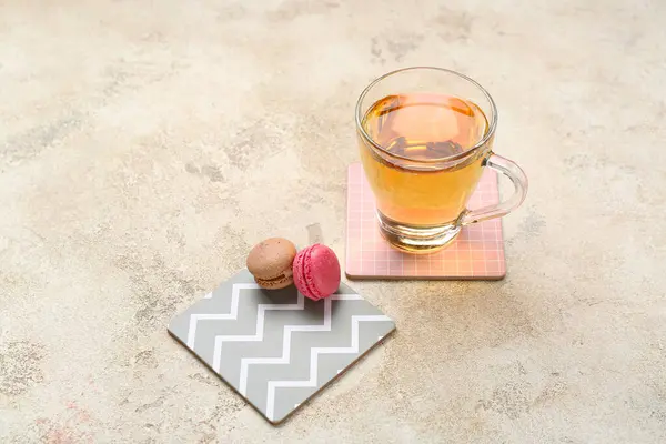 Drink coasters with cup of tea and macaroons on grey grunge table