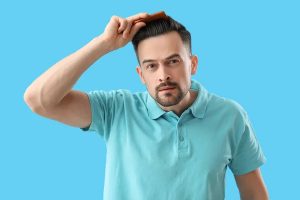 Besorgter Junger Mann Kämmt Haare Auf Blauem Hintergrund — Stockfoto