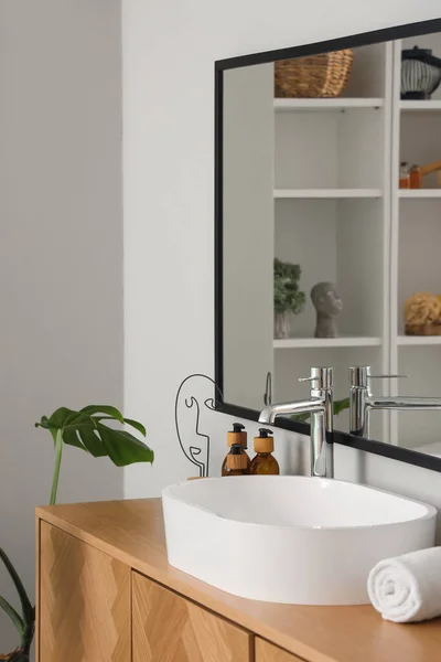 stock image White sink with bath accessories on chest of drawers in room