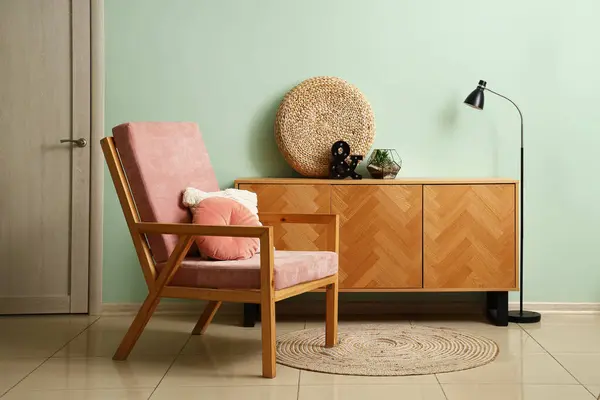 Interior of living room with pink wooden armchair and drawers