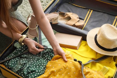 Elbiselerini yeşil halıya yerleştiren genç kadın, yakın plan.