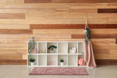 Odanın ahşap duvarının yanında bitki ve dekor olan televizyon standı.