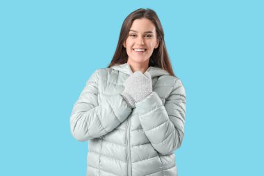 Young woman in winter clothes on blue background