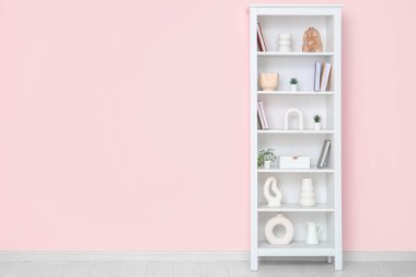 Pembe duvarın yanındaki modern raf ünitesi