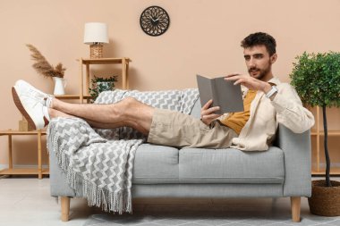 yakışıklı adam evde kanepede kitap okuma