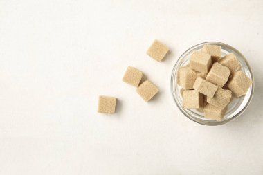 Beyaz arka plan üzerinde kahverengi şeker kamışı küpleriyle kase