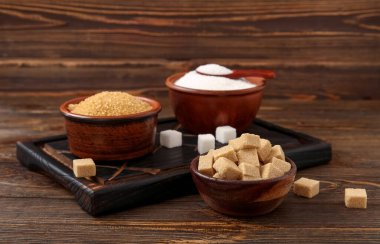 Tahta arka planda farklı tipte şekerli kaseler