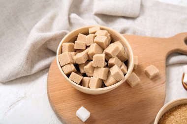 Beyaz arka plan üzerinde kahverengi şeker kamışı küpleriyle kase