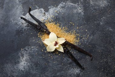 Aromatik vanilya şekeri, çiçek ve siyah arkaplanda çubuklar