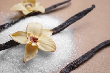 Bir yığın aromatik vanilya şekeri, çiçek ve bej arka planda çubuklar.