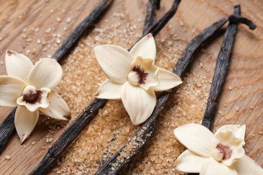 Aromatik vanilya şekeri, çiçekler ve tahta arka planda çubuklar