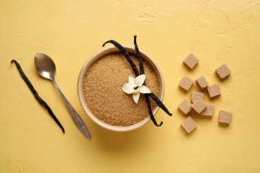 Aromatik vanilya şekeri, çiçek ve sarı zemin üzerine yapışmış bir kase.