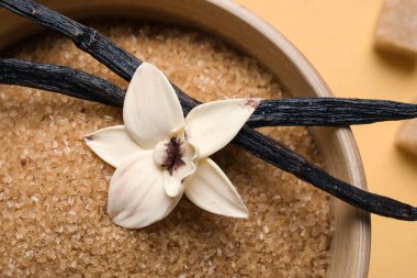 Aromatik vanilya şekeri, çiçek ve sarı zemin üzerine yapışmış bir kase.