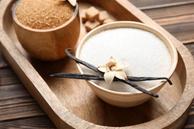 Aromatik vanilya şekerli kaseler, çiçek ve tahta arka planda sopalar.