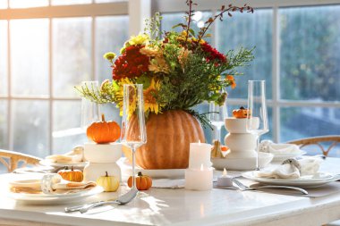 Farklı sonbahar çiçekleri servis edilen yemek masasında balkabağında.