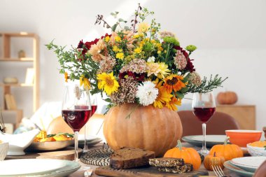 Şenlikli yemek masasında sonbahar çiçekli balkabağı, yakın plan.