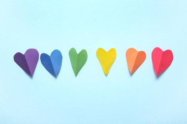 Mavi arka planda kağıttan yapılmış renkli kalpler. LGBT kavramı
