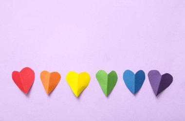 Leylak arka planında kağıttan yapılmış renkli kalpler. LGBT kavramı