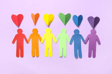 Renkli kağıt kalpler ve leylak arka planda insan figürleri. LGBT kavramı