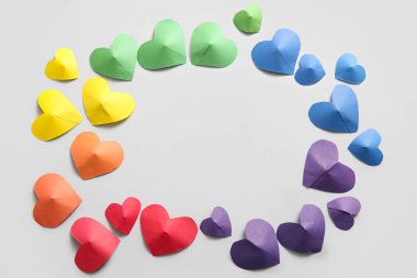 Gri arkaplanda renkli kağıt kalplerden yapılmış bir çerçeve. LGBT kavramı