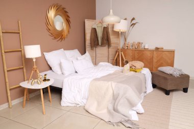 Yatak ve lambaların üzerinde kışlık giysiler olan rahat bir yatak odası.