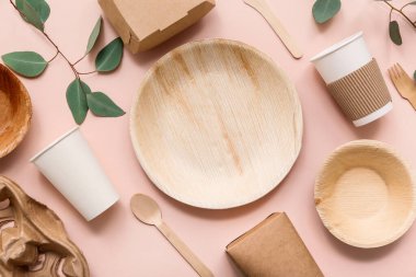 Pembe arka planda bitki dalı olan tek kullanımlık eko tablo takımı