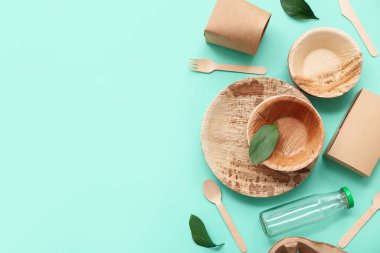 Turkuaz arka planda yaprakları olan tek kullanımlık eko tablo takımı