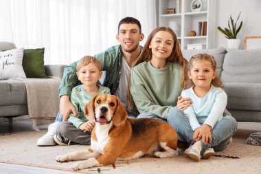 Aileleri ve Beagle köpeğiyle evde yerde yatan küçük çocuklar.
