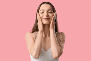 Pembe arka planda yüz geliştirme egzersizi yapan genç kadın, yakın plan.