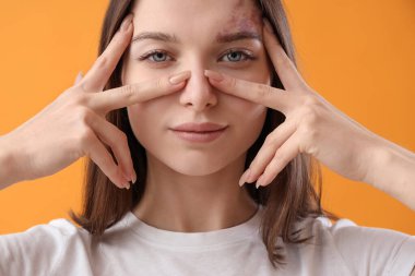 Sarı arka planda yüz geliştirme egzersizi yapan genç kadın, yakın plan.