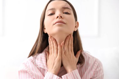 Yatak odasında yüz geliştirme egzersizi yapan genç bir kadın.