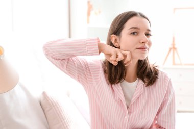 Yatak odasında yüz geliştirme egzersizi yapan genç bir kadın.