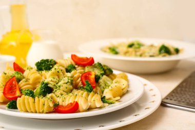 Brokolili lezzetli makarna tabakları ve beyaz arka planda domatesler