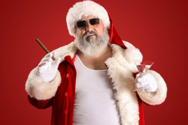 Kırmızı arka planda purosu ve kokteyli olan kötü Noel Baba.