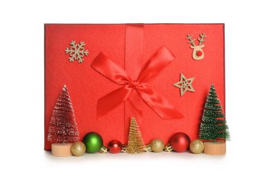 İçinde Noel ağaçları, toplar ve beyaz arka planda tahta oyuncaklar olan hediye kutusu.