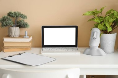 Ofisinde kitaplar ve bitkiler olan boş bir laptop.