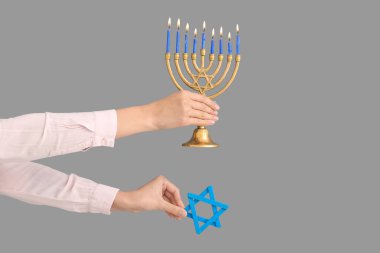 Menoralı kadın eller ve gri arka planda David Star. Hanuka kutlaması