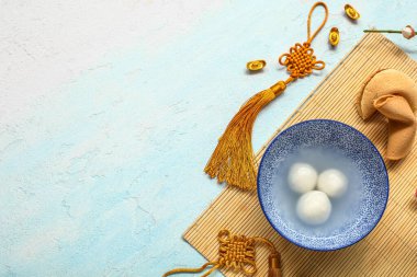 Bambu hasırı, bir kase tangyuan, Çin dekoru ve mavi arka planda fal kurabiyesi. Dongzhi Festivali