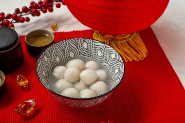 Bir kase tangyuan, çay ve Çin dekoru kırmızı hasırda, yakın plan. Dongzhi Festivali
