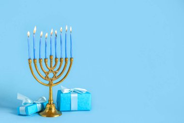 Renkli arkaplanda Hanuka kutlaması için yanan mumlar ve hediyelerle Menorah.