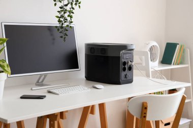 Modern bilgisayar ve taşınabilir güç istasyonu ile rahat çalışma alanı