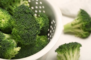 Beyaz arka planda taze brokolili Colander, yakın plan.