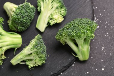 Siyah arka planda taze brokoli lahanası olan bir tahta.