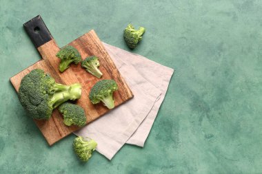 Tahta tahta tahta, yeşil arka planda taze brokoli lahanaları.