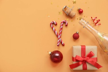 Turuncu arka planda Noel dekoru olan şampanya şişesi.