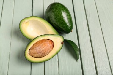 Taze olgun avokadolar ve yeşil ahşap arka planda yaprak.