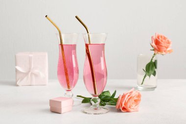 Beyaz arka planda yüzük kutusu ve güllerle dolu lezzetli kokteyller. Sevgililer Günü kutlaması