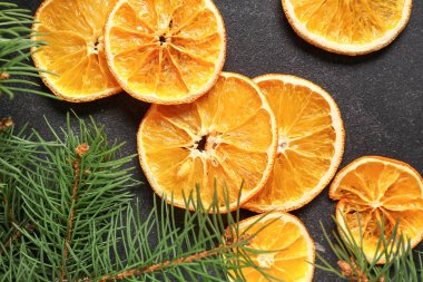Kurumuş portakal dilimleri ve siyah arkaplanda köknar dalları